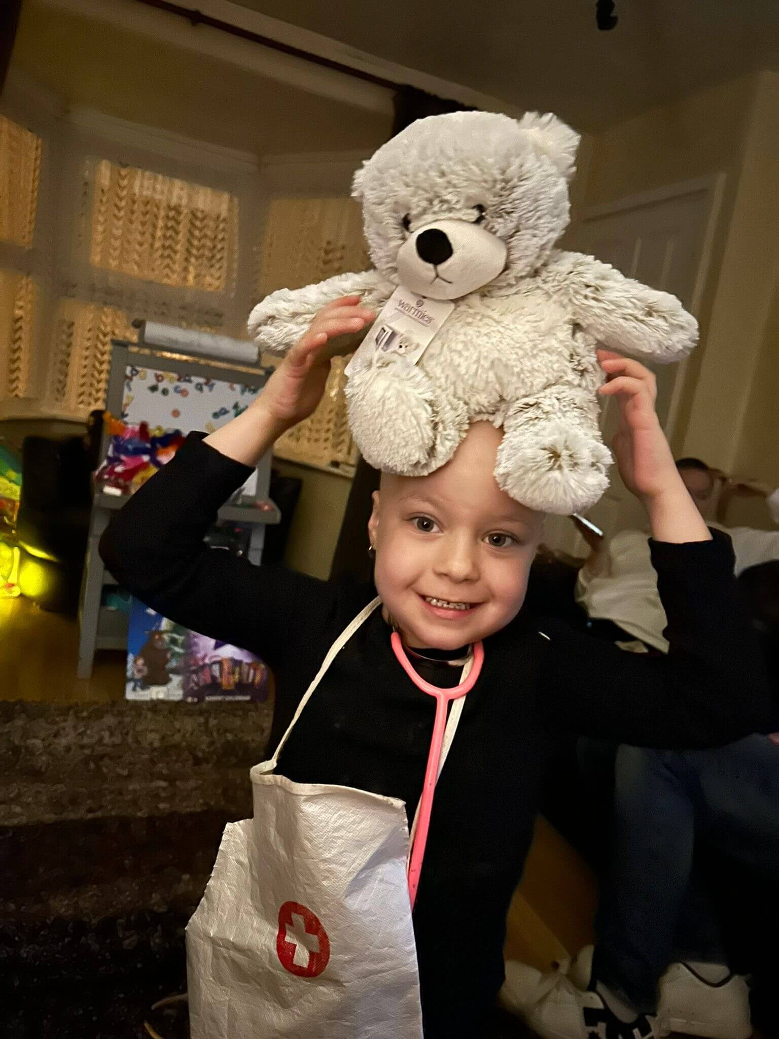 Little girl holding her cuddly sensory ted on her head