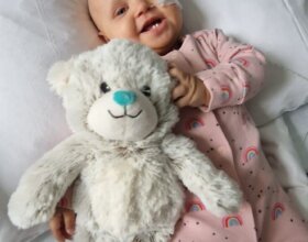 Cuddly ted with green nose held by cute baby girl